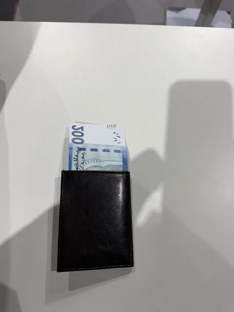 Un porte-monnaie noir et un billet publicitaire .